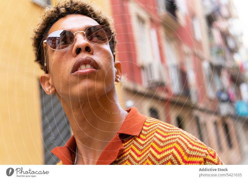 Stylish ethnic man walking on city street style traveler urban confident listen trendy explore male young hispanic tourist vacation lifestyle colorful tourism