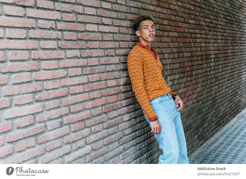 Pensive ethnic man standing on the street style color urban orange using modern young male trendy lifestyle hipster headlight colorful millennial fashion