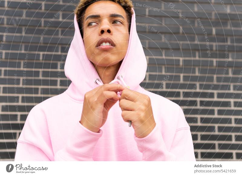 Young ethnic man in pink hoodie style confident hipster urban fashion outfit serious young trendy modern male curly hair afro individuality millennial
