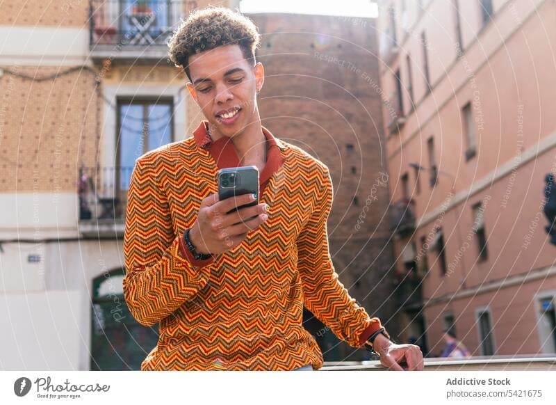 Ethnic man using smartphone in city urban style browsing modern sunlight mobile male young hispanic latin american gadget trendy message device surfing