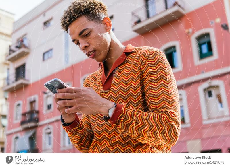 Ethnic man using smartphone in city urban style browsing modern sunlight mobile male young hispanic latin american gadget trendy message device surfing