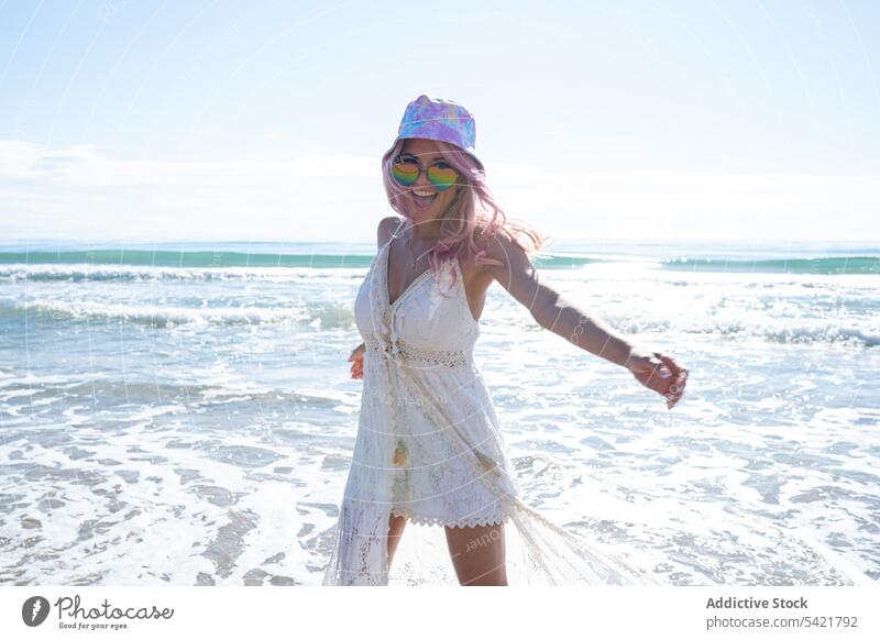 Carefree woman enjoying vacation near sea beach summer carefree freedom holiday shore female pink hair dyed hair coast smile cheerful ocean dress happy seaside