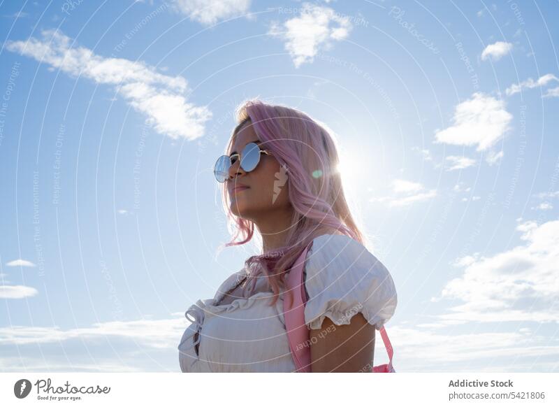 Stylish woman with pink hair standing against sea in summer vacation holiday trendy style sunglasses summertime female water ocean blue sky coast freedom