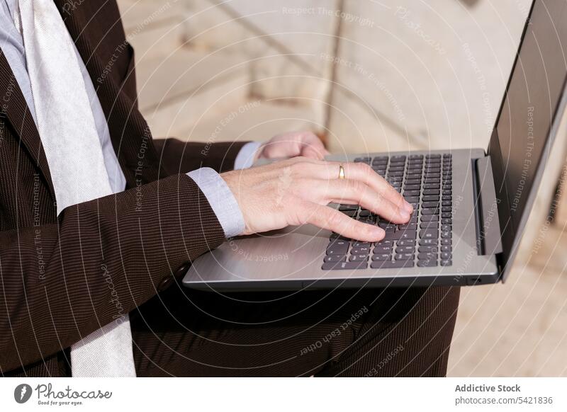 Anonymous mature man in suit using laptop on stairs businessman online remote style gadget internet communicate entrepreneur positive middle age aged male