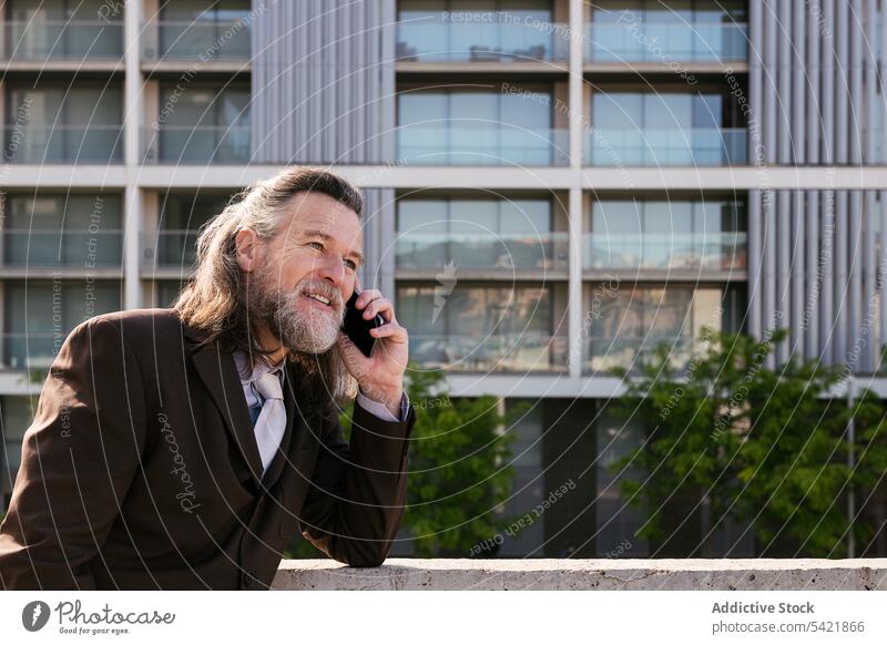Happy bearded businessman speaking on smartphone in city talk urban smile communicate style happy modern mature middle age gray hair elegant phone call