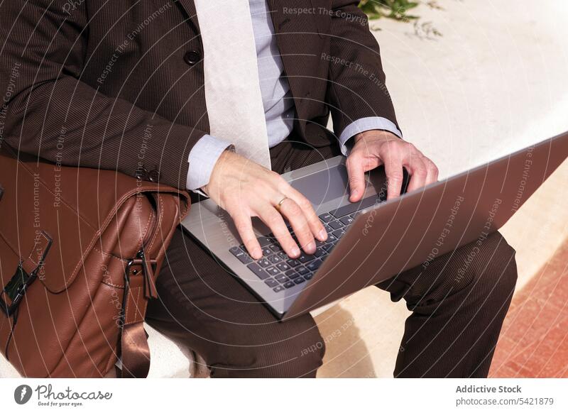 Mature businessman working on laptop on street using online remote style urban digital internet gadget typing communicate entrepreneur positive middle age