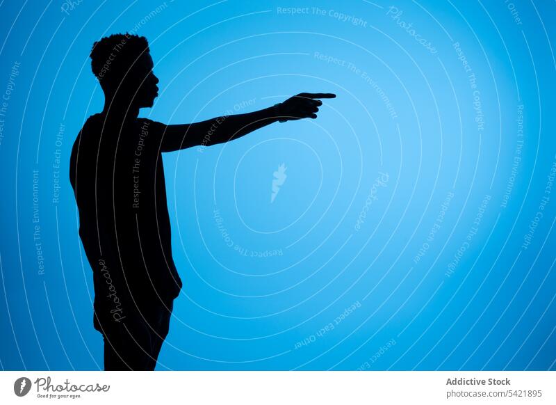 Silhouette of black man pointing aside in studio point away silhouette outstretch index finger gesture sign male african american ethnic show direction
