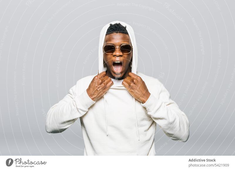 Black rebellious man shouting in studio scream hoodie style yell expressive trendy male ethnic black african american fashion outfit model individuality