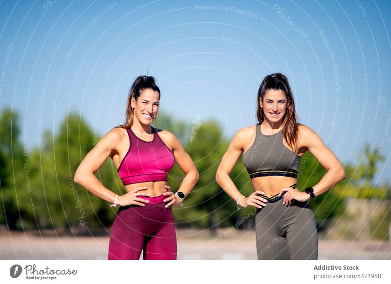 Cheerful sporty twins standing on asphalt women fit sister together cheerful positive activity lifestyle smile fitness female content optimist glad slim delight
