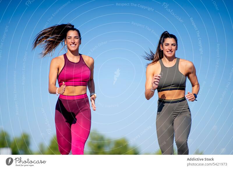 Cheerful sporty twins running together jog fit fitness training women ponytail sister cheerful positive activity lifestyle stand smile female content optimist