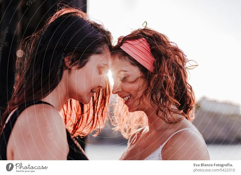 young lesbian couple hugging at sunset outdoors. Lifestyle and pride concept. love is love friends casual lifestyle gay urban cheerful girlfriend standing