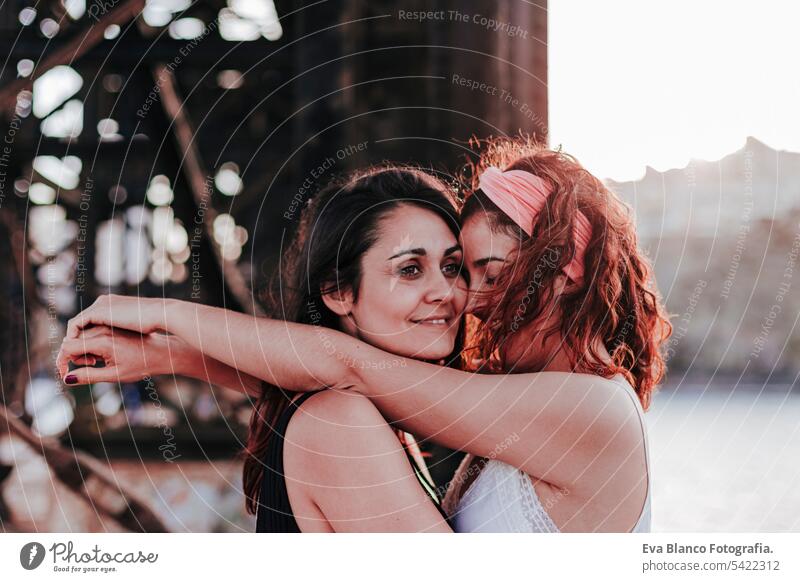 young lesbian couple hugging at sunset outdoors. Lifestyle and pride concept. love is love friends casual lifestyle gay urban cheerful girlfriend standing