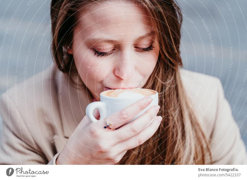 portrait of beautiful caucasian woman on a terrace drinking coffee. urban and lifestyle concept close up cafe smoothie croissant breakfast outdoors mobile phone