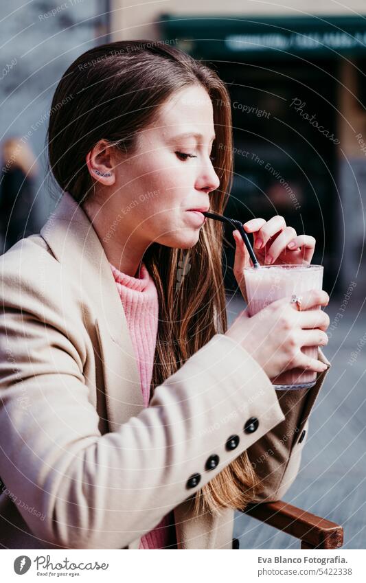 portrait of beautiful caucasian woman on a terrace drinking a smoothie. urban and lifestyle concept close up cafe croissant breakfast outdoors mobile phone