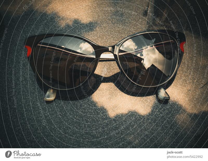 Glasses with dark tinted lenses resting on table top and reflecting the sky Sunglasses Woman Reflection stylish Sky Clouds Summer Table edge Tabletop Style