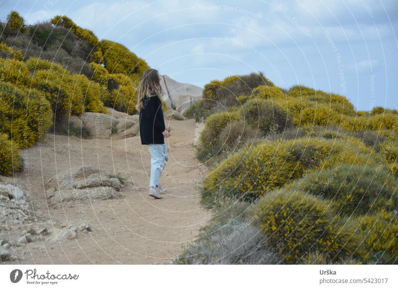 A girl on a path between flowers in Sardegna Girl Nature travel long hair Yellow plants rocks stones sardegna Bushes Spring daylight Sardinia