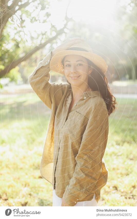 beautiful 30 year old millennial woman in hat and olive green linen shirt in the park with soft sunlight autumn or summer portrait Woman Portrait photograph