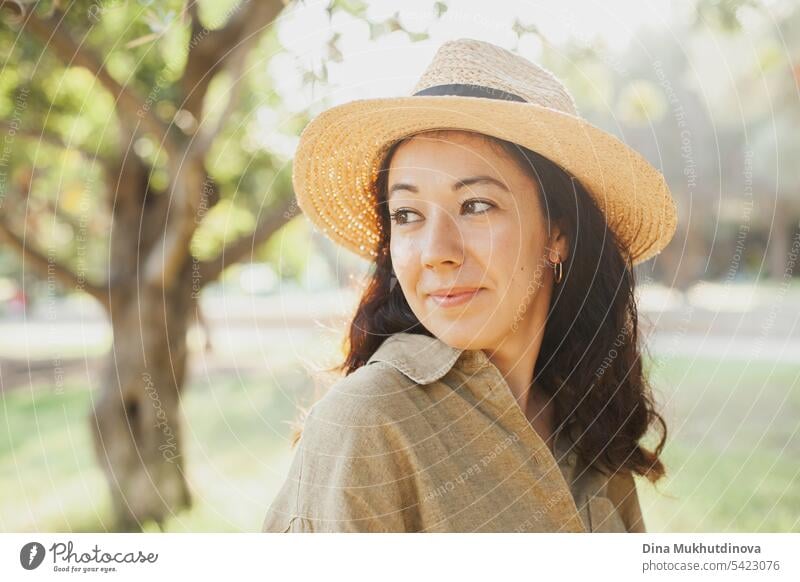 beautiful 30 year old millennial woman face closeup in hat and olive green linen shirt in the park with soft sunlight autumn or summer portrait Woman