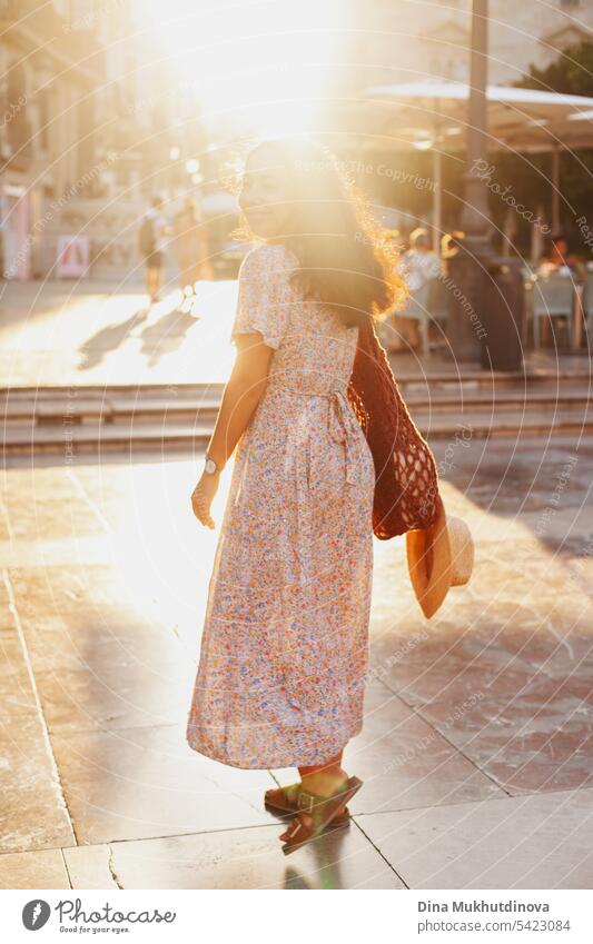 beautiful brunette woman tourist in European city smiling at sunset in summer, walking on the street. Female solo traveler looking to the camera in Valencia, Spain.