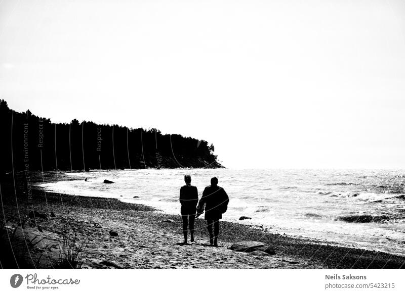 Silhouette of couple on the beach at sunset. Black and white photo. man female black and white dark freedom vintage black and white photography touching evening