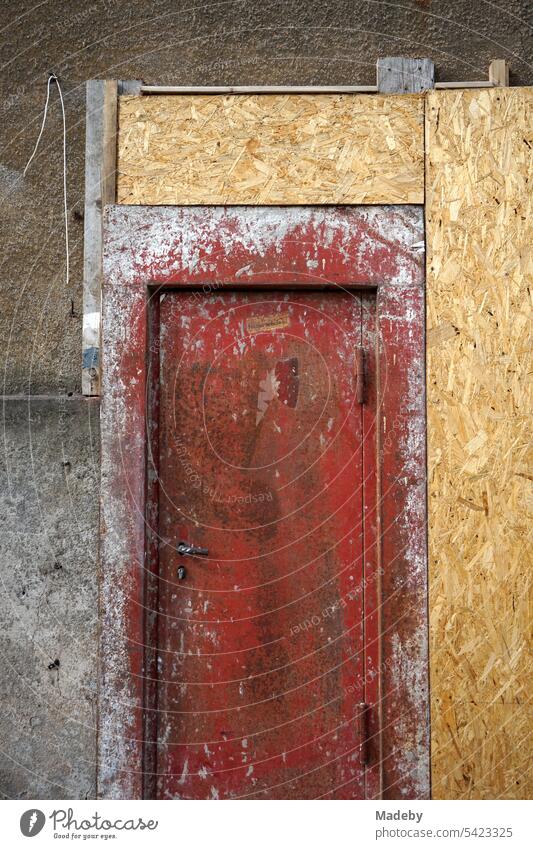Fire door in an old dilapidated facade with temporary chipboard in natural colors of an old building in Detmold at the Teutoburg Forest in East Westphalia-Lippe
