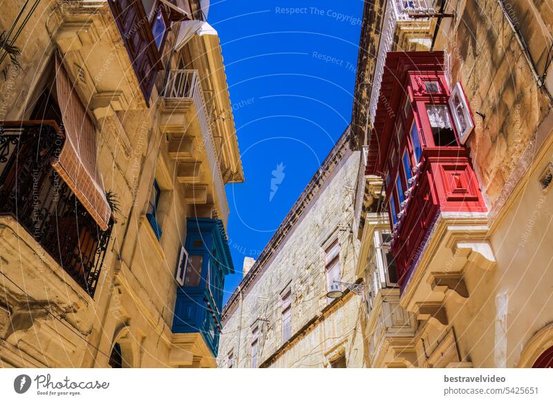 Traditional Maltese limestone buildings with coloured balconies in the vibrant alleys of the old city Birgu, Citta Vittoriosa without crowd.
