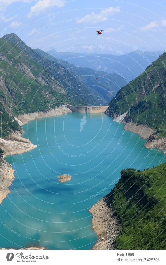 Helicopter flies over the reservoirs near Kaprun Reservoir Austria Flying Rotor Lake Water Retaining wall dam Energy work Transport transport Alps mountain