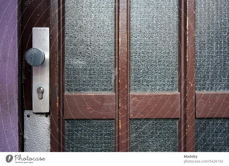 Old front door of brown wood with ribbed glass and door handle in the style of the post-war period in the Hanauer Landstraße in the Ostend of Frankfurt am Main in Hesse