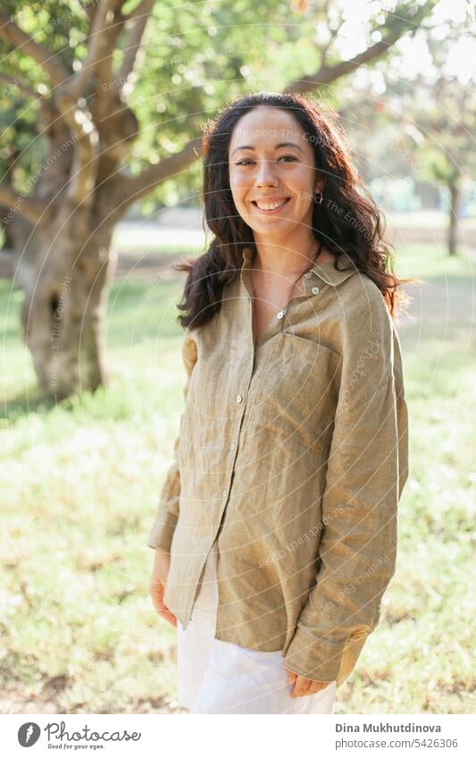 beautiful 30 year old millennial woman smiling olive green linen shirt casual portrait in the park with soft sunlight autumn or summer portrait Woman