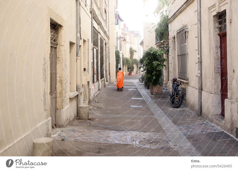Side street in Arles Orange Woman Rear view Street Alley urban doors houses Architecture Stone Perspective Escape Historic Old town Facade plants off