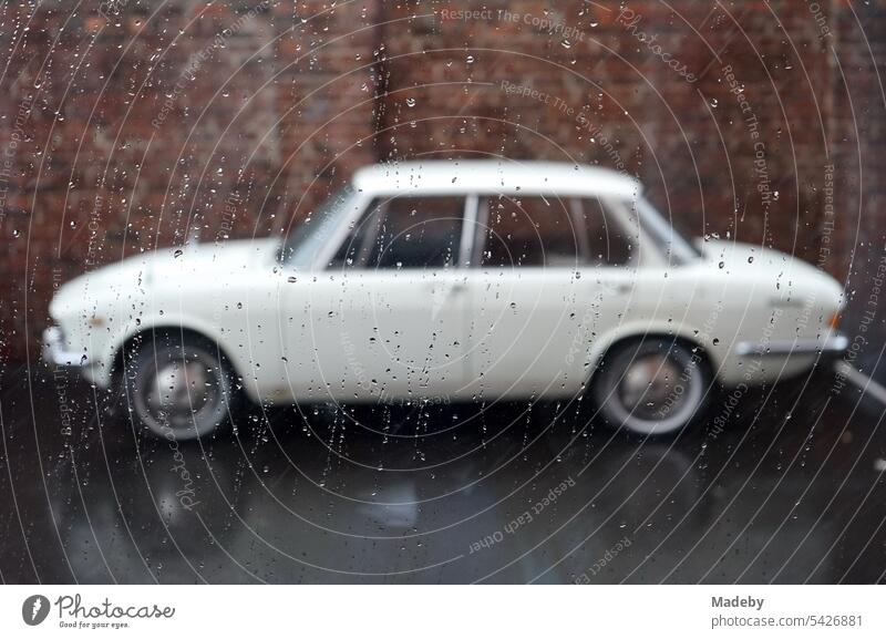 View out the window of a white Japanese sedan of the sixties and seventies in the rain in the Klassikstadt in the district of Fechenheim in Frankfurt am Main, Hesse