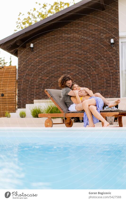 Young couple relaxing by the swimming pool in the house backyard adult attractive background beautiful bikini caucasian cheerful cosy cute female fresh fun