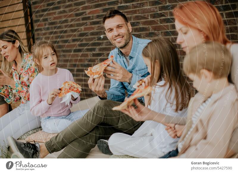 Group of young people and kids eating pizza in the house backyard atmosphere caucasian child children couple daughter drink enjoy family fast food father female