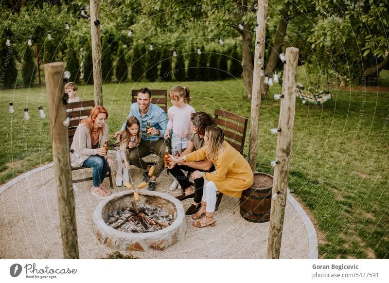 Friends having good time and baking corns in the house backyard adult barbecue bbq casual caucasian charcoal grill cheerful closeup corn on the cob delicious