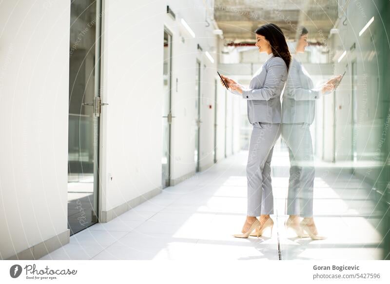 Young business woman using cell phone in office hallway Woman Caucasian Office Professional Businesswoman Hallway people Telephone person Self-confident