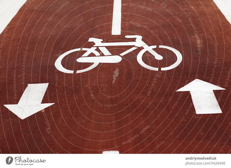 New marking bike path. White bicycle symbol and two oposite arrows on red asphalt lane, road. Bicycle path in the city. Two-way cycle lane on an avenue. Lifestyle. Urban traffic and transportation