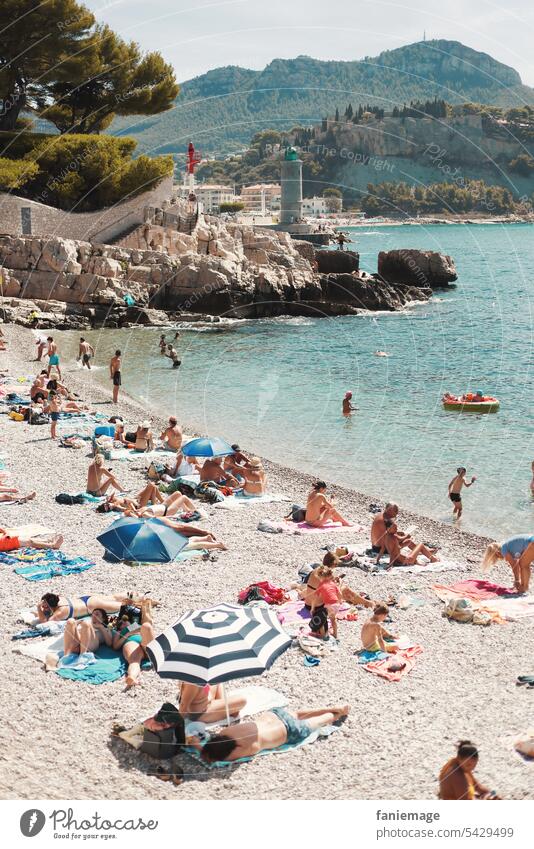 Badegäste am Bestouan Strand von Cassis mit Leuchtturm im Hintergrund Mittelmeer Sonnenschirme Urlauber Plage du Bestouan Kiesstrand klares Wasser türkis