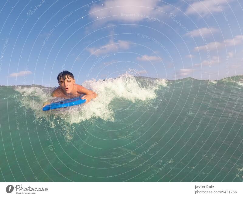 boy bodyboarding a wave on a turquoise water beach on a sunny summer day, bodysurfing, fun at the beach, copy space holiday sea child jet joy splash surfer