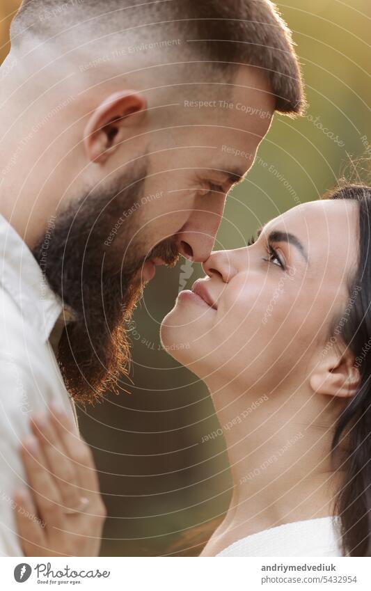 St. Valentines day. Portrait happy stylish loving couple is hugging in sunny park on warm day. Young bearded man and brunette woman are enjoying each other on date or celebrating anniversary outdoors
