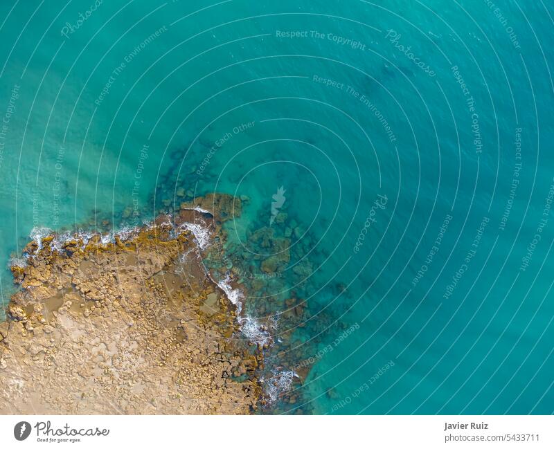 view from above of a rocky sea ledge, in a sea of crystal clear turquoise waters, cape rocky, coastline, drone view seaside shore zenithal top view ocean aerial