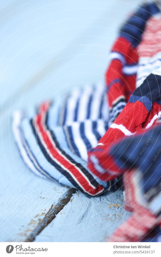 red white and blue striped fabric on light blue wood Cloth Striped fabric red white blue White Red Blue Maritime Pattern Wood backing Exterior shot Rustic