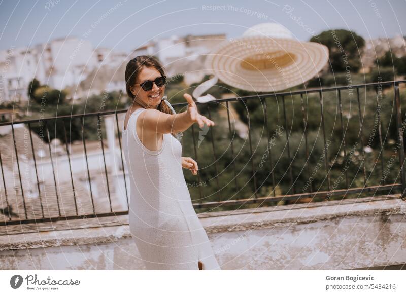 A young woman in a white dress throw hat during tourist visit in Alborebello, Italy alborebello italy italian throwing beautiful girl activity traveler adult