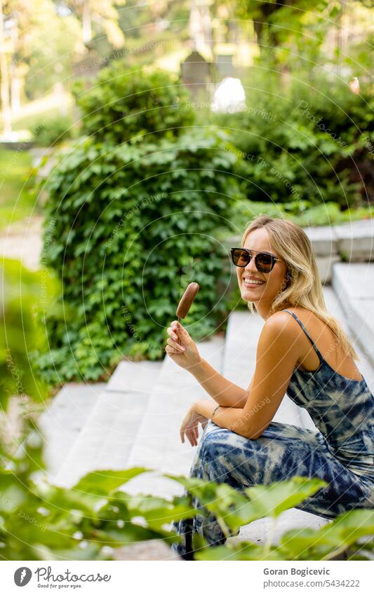 Pretty young woman sitting on stairs and eating ice cream white caucasian summer happy adult style outside lifestyle food beautiful fun portrait sun joy holding