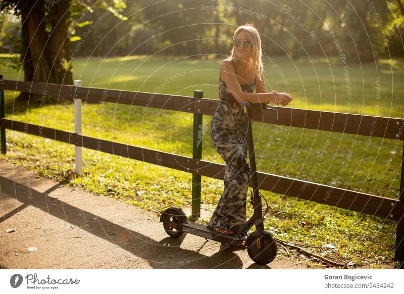 Young woman with an electric scooter in the park on a sunny summer day active activity attractive beautiful casual caucasian city eco female fun gadget happy