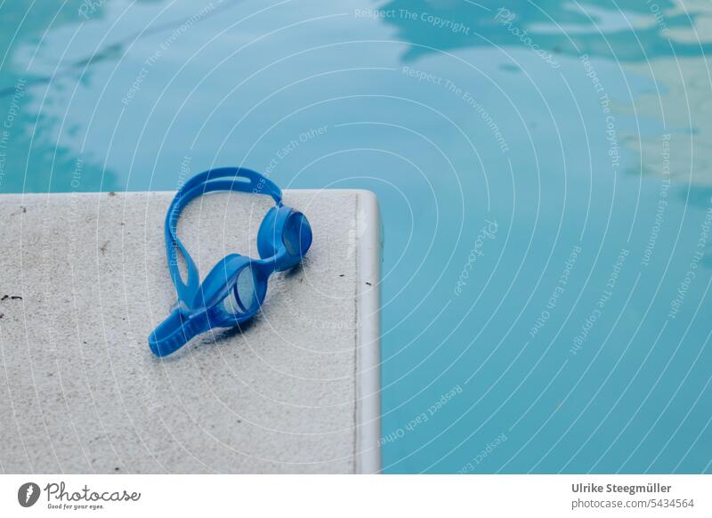 A blue diving goggles lies on a white diving board at the blue pool Summer vacation Blue Springboard be afloat Dive Diving goggles children