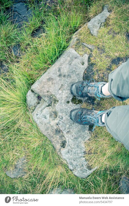 A person with wet shoes stands on a stone. The camera's view is directed downwards from the first-person perspective. wet feet Wet sodden Hiking stroll trekking