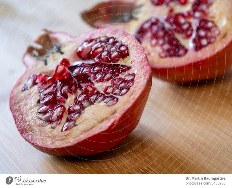 A pomegranate, halved with seeds and red seed coat (aril); medium format photograph. Pomegranate Fruit fruit Sámen Seed coat Aril berry Ancient crop Close-up