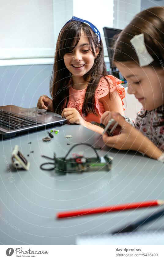 Happy female student smiling while looking to classmate assembling machine pieces happy children assemble electronic circuit electrical portrait fun young