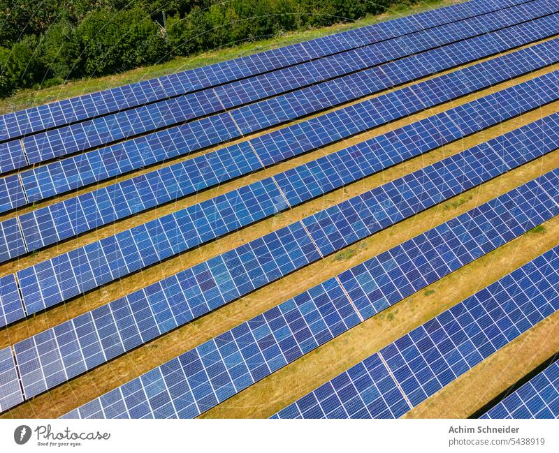 Aerial view of a ground-mounted photovoltaic system with many solar modules in sunshine Aerial photograph solar power plant series photovoltaics Modules Rural