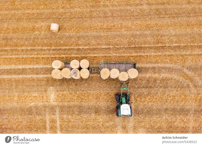Aerial view of tractor with pitchfork loading hay bales on trailer stubble field aerial view harvest dry autumn straw bale pattern hot summer hanger germany